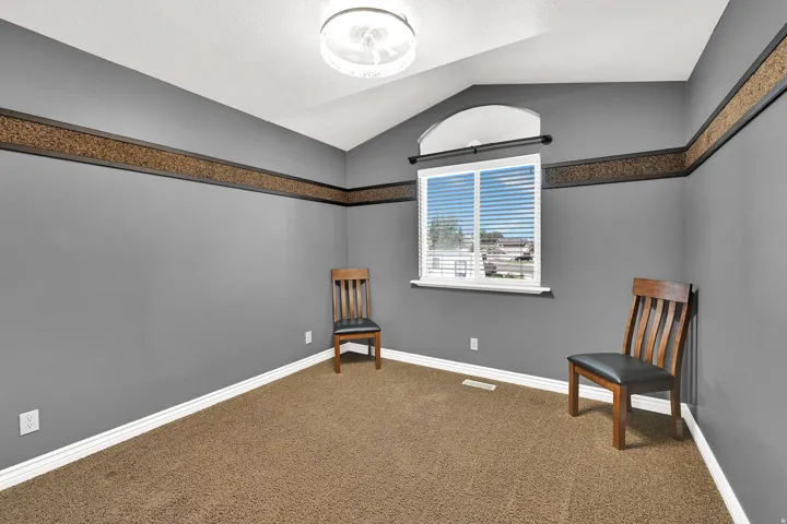 Vaulted ceiling with an arched window, white trim, wall-mounted light fixture, and textured wall border