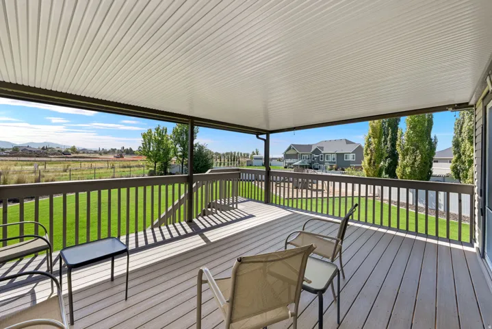Covered deck featuring a composite wood-finish surface, wood railing, and a slatted ceiling