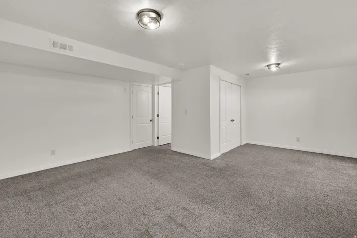 Neutral gray carpeting, white walls, white doors, and flush-mount ceiling lighting