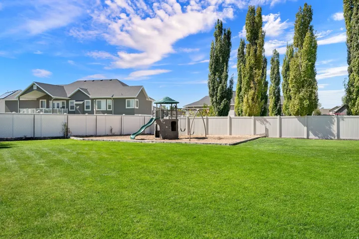 Expansive green lawn with a white privacy fence