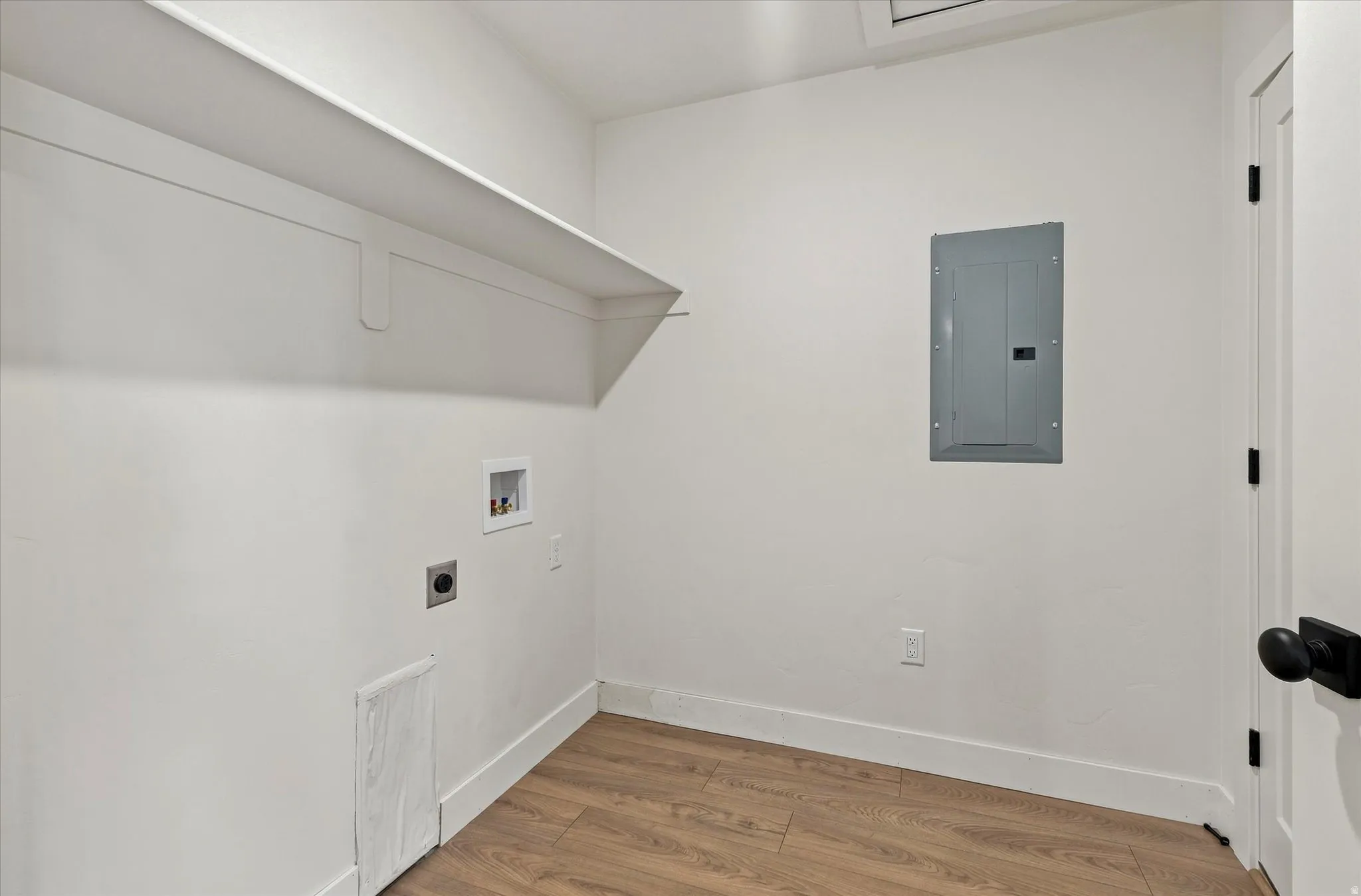 Utility room with a built-in shelf, wood-finish flooring, and white walls