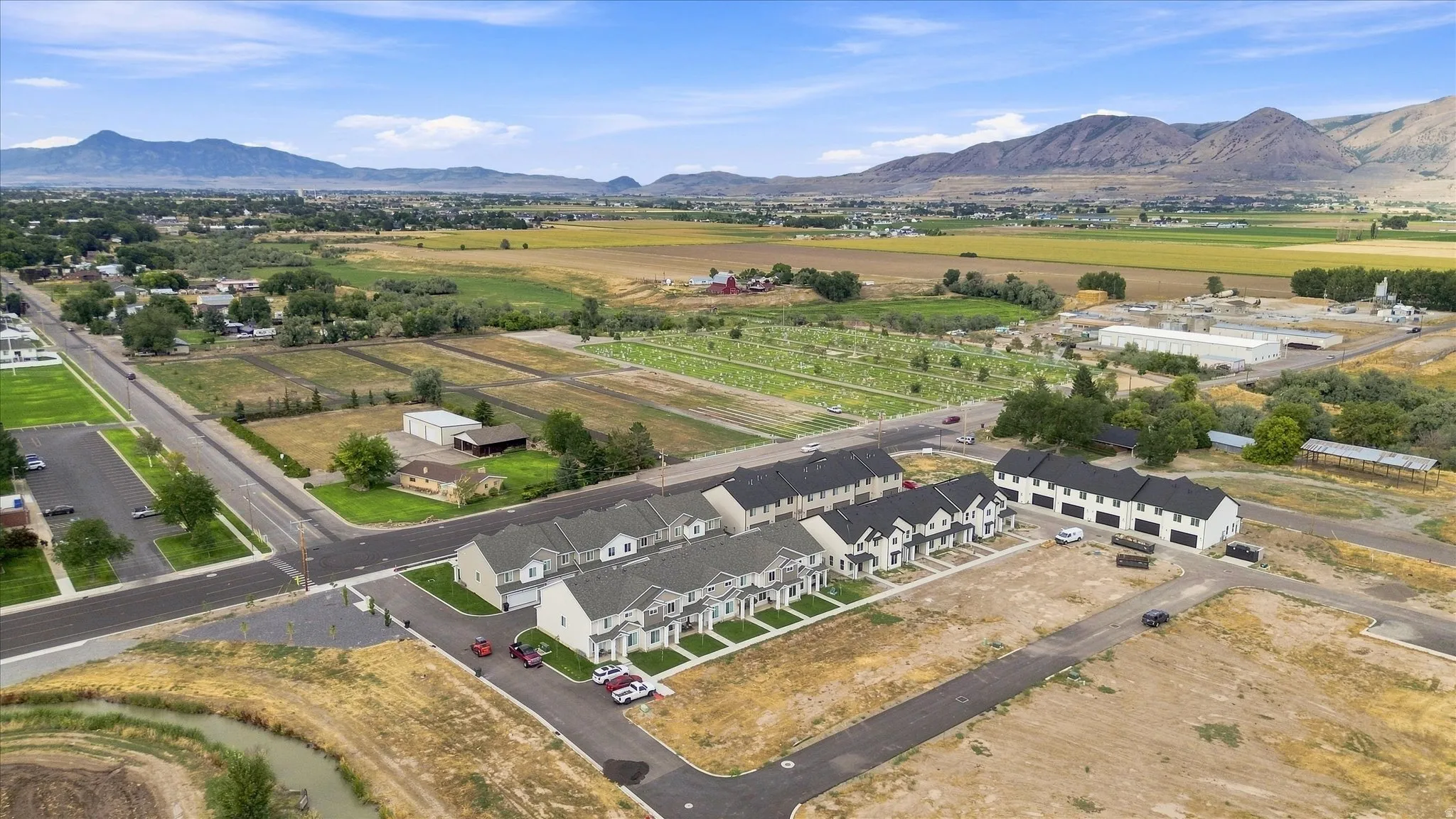 Multiple newly constructed townhome-style residences with a neutral exterior palette and dark roofs