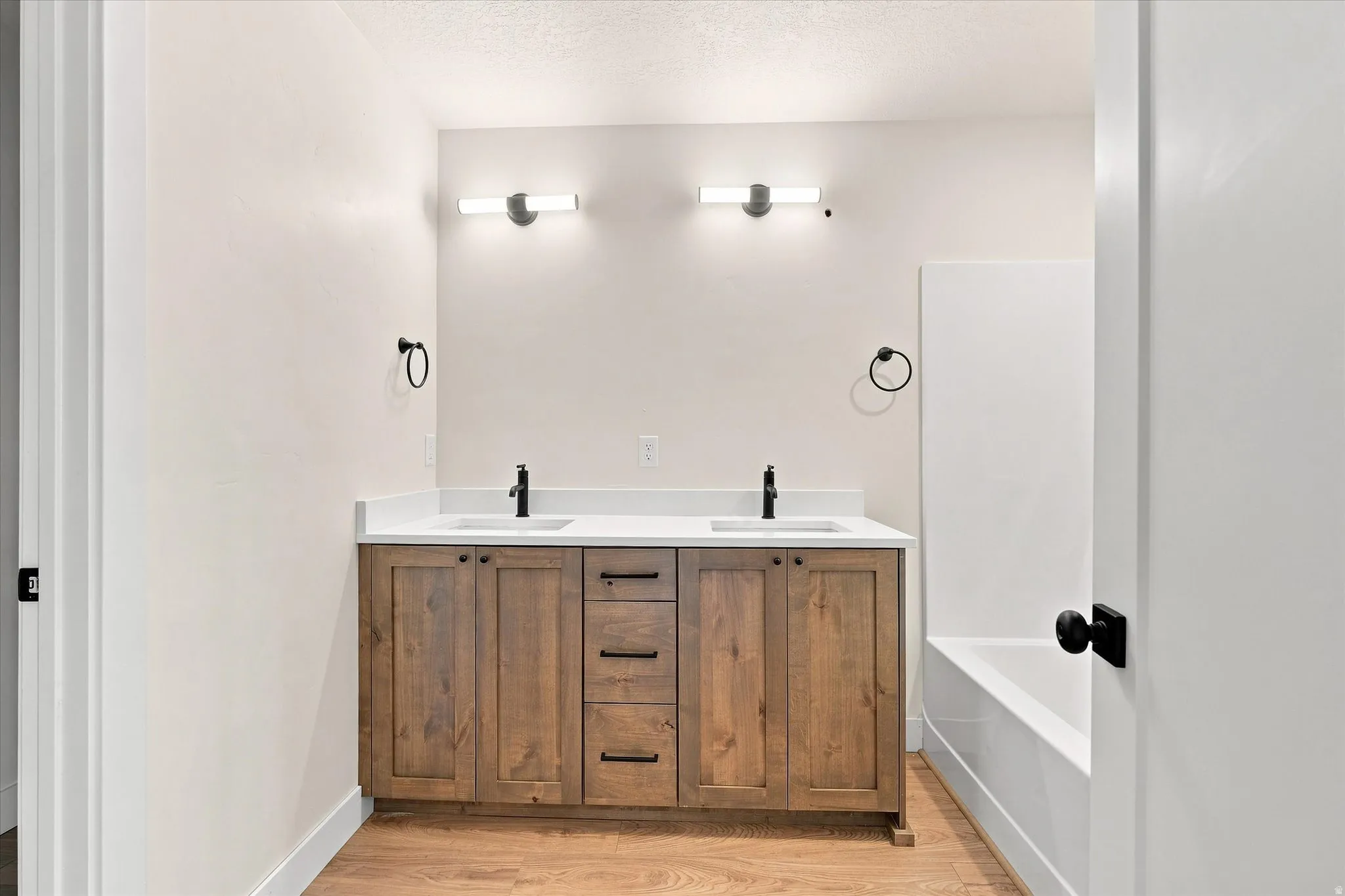 Dual vanity with wood-finish cabinetry, white countertop, and integrated sinks