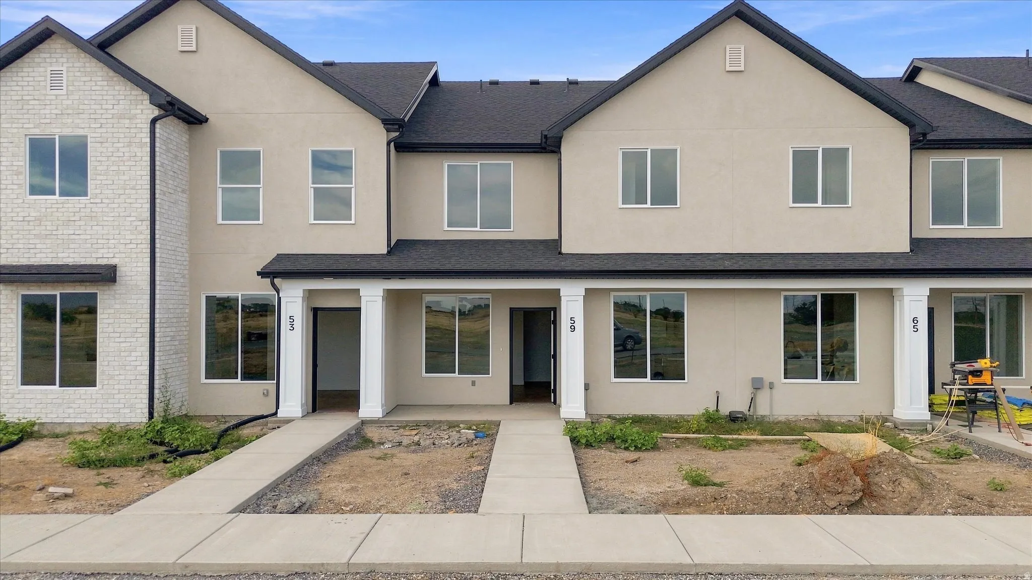 Modern townhome exterior featuring light-colored stucco and brick accents