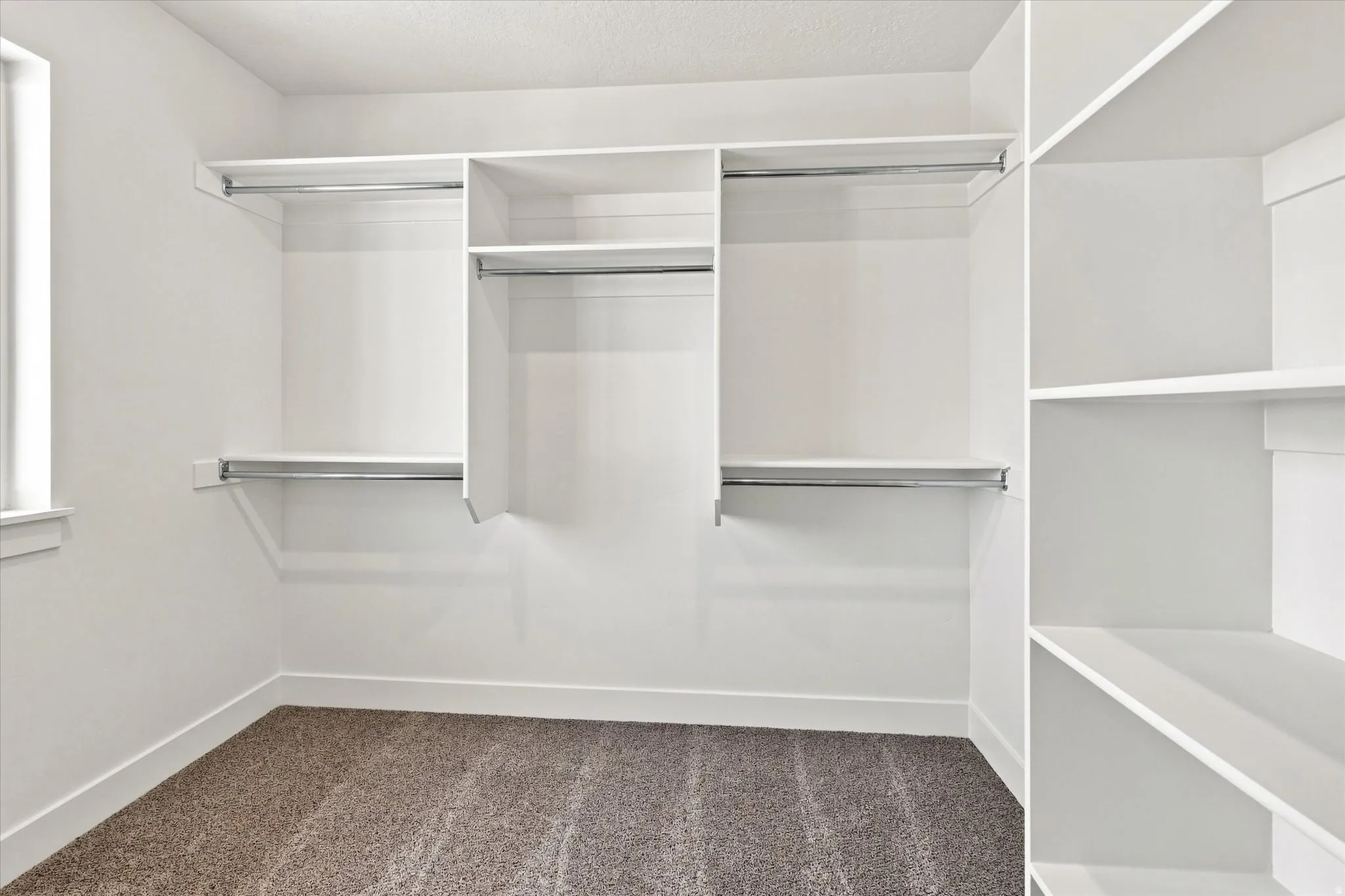 Built-in white shelving system with hanging rods, integrated shelving units, and plush carpeting