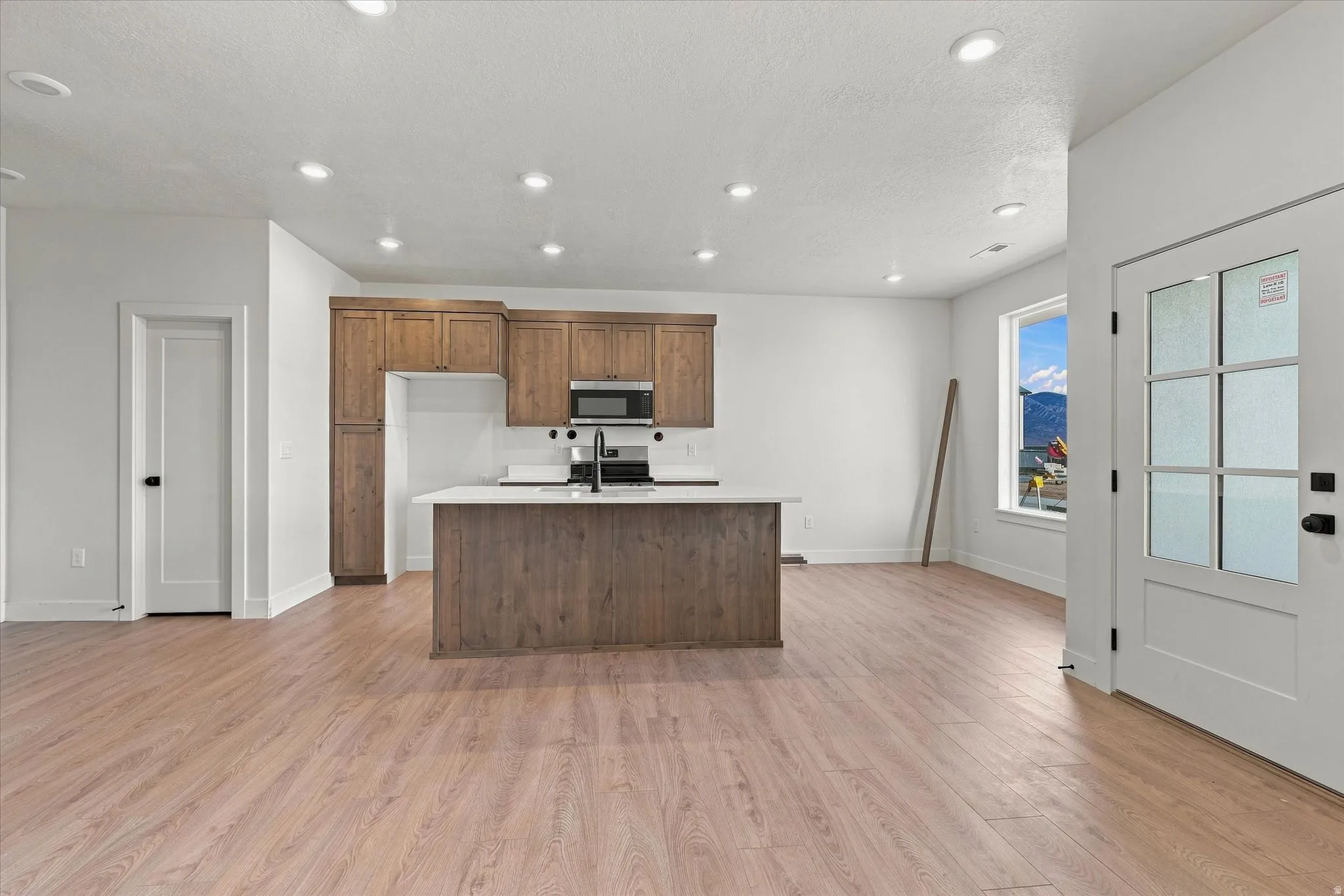 Open-concept kitchen featuring wood-finish cabinetry, a central island with a white countertop, and recessed lighting
