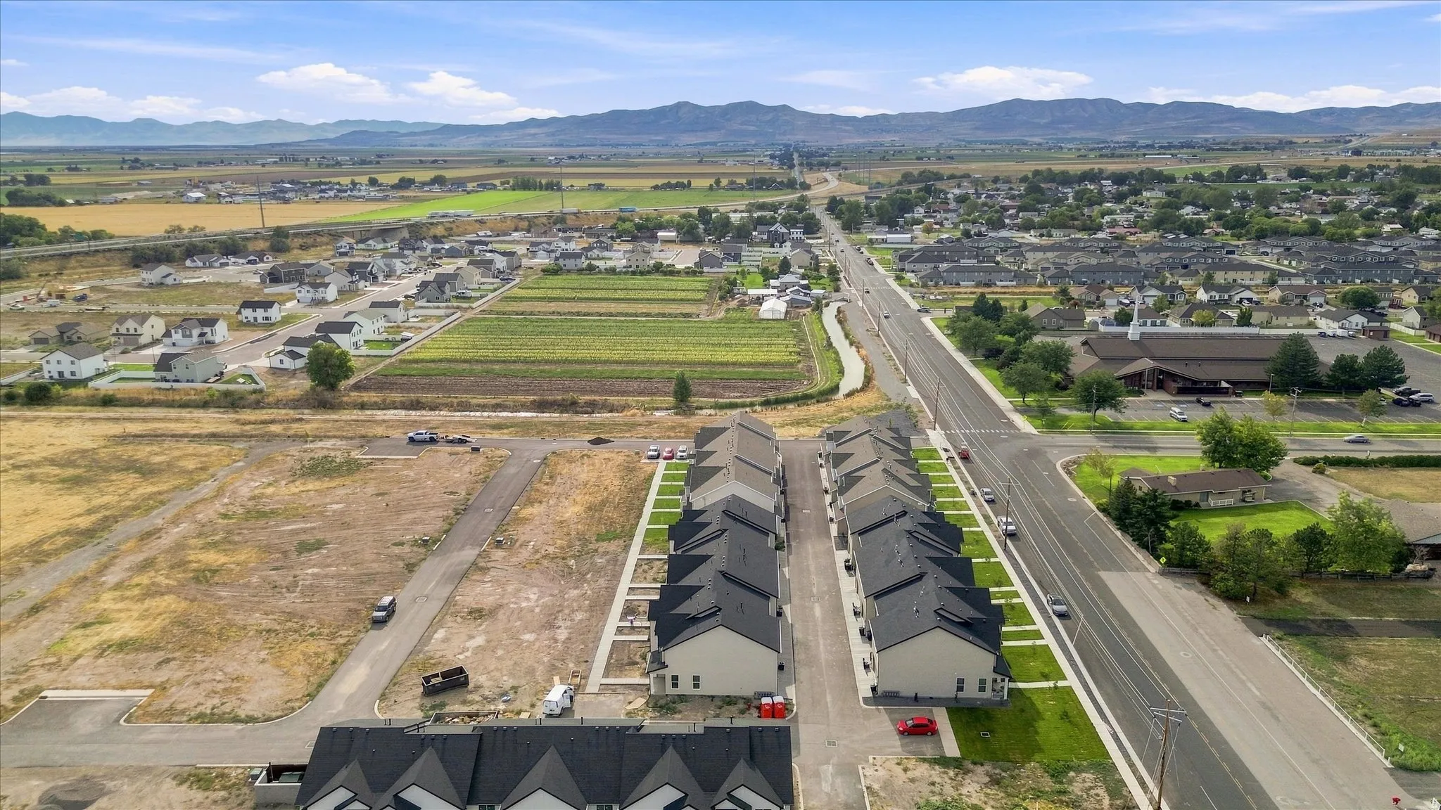 Residential development featuring newly constructed townhomes and undeveloped plots with mountain scenery