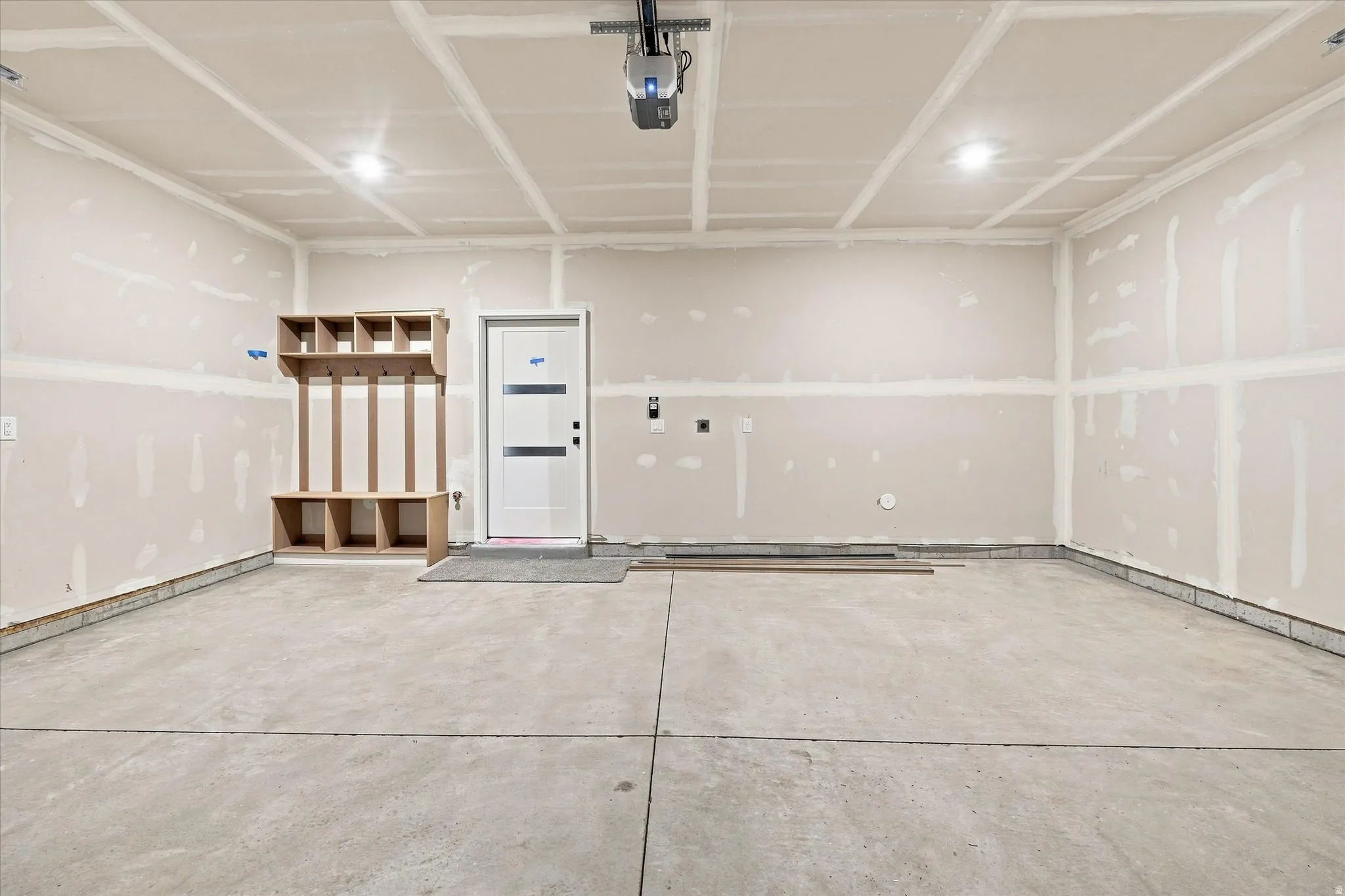 Spacious garage with exposed drywall, concrete flooring, and built-in storage shelving