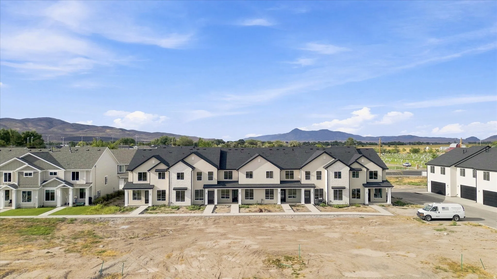 Contemporary townhomes featuring light-colored stucco exteriors and dark roofing, multiple windows, and covered entryways