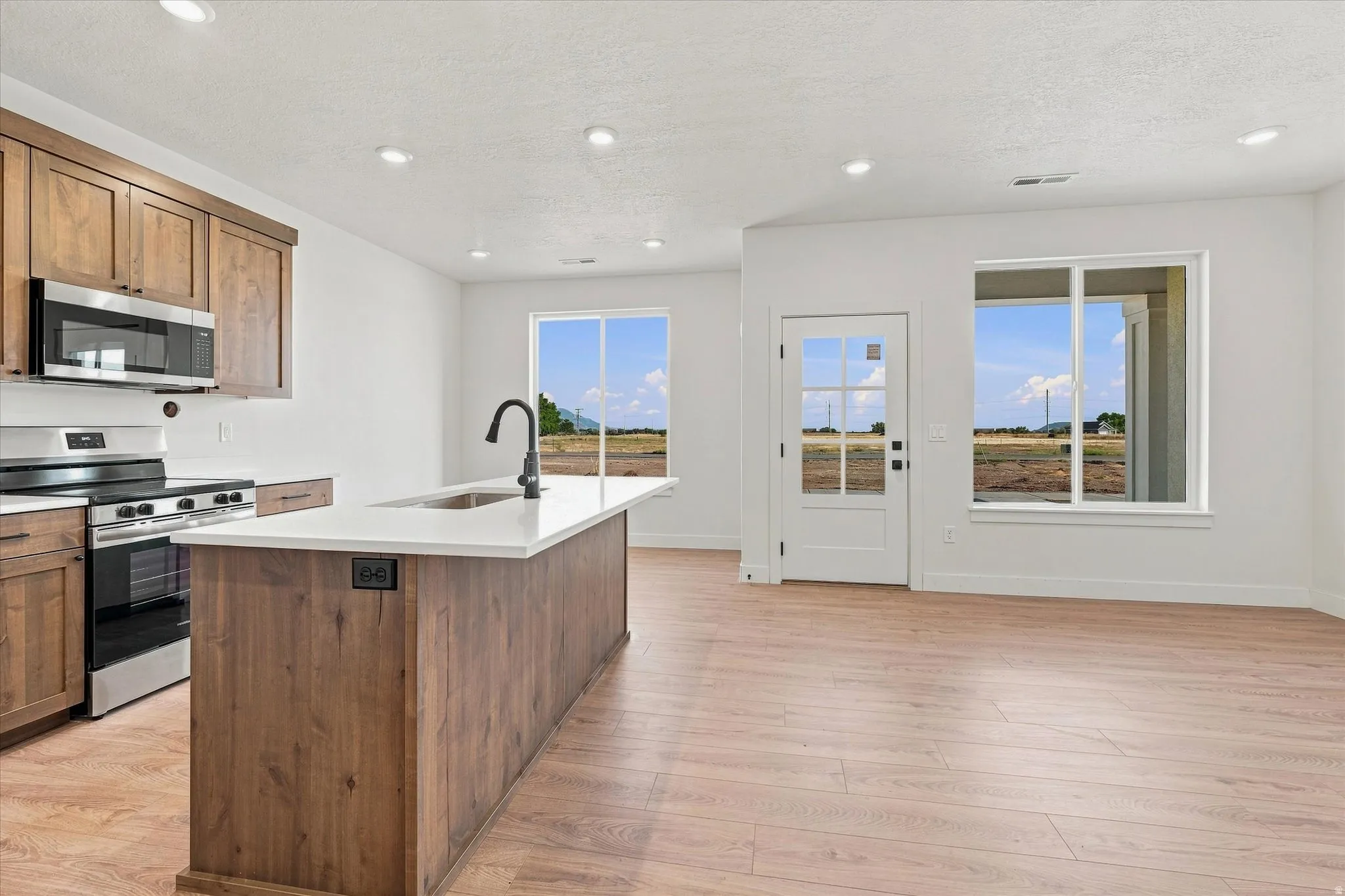 Open-concept living space with wood-finish flooring, recessed lighting, and ample natural light through large windows