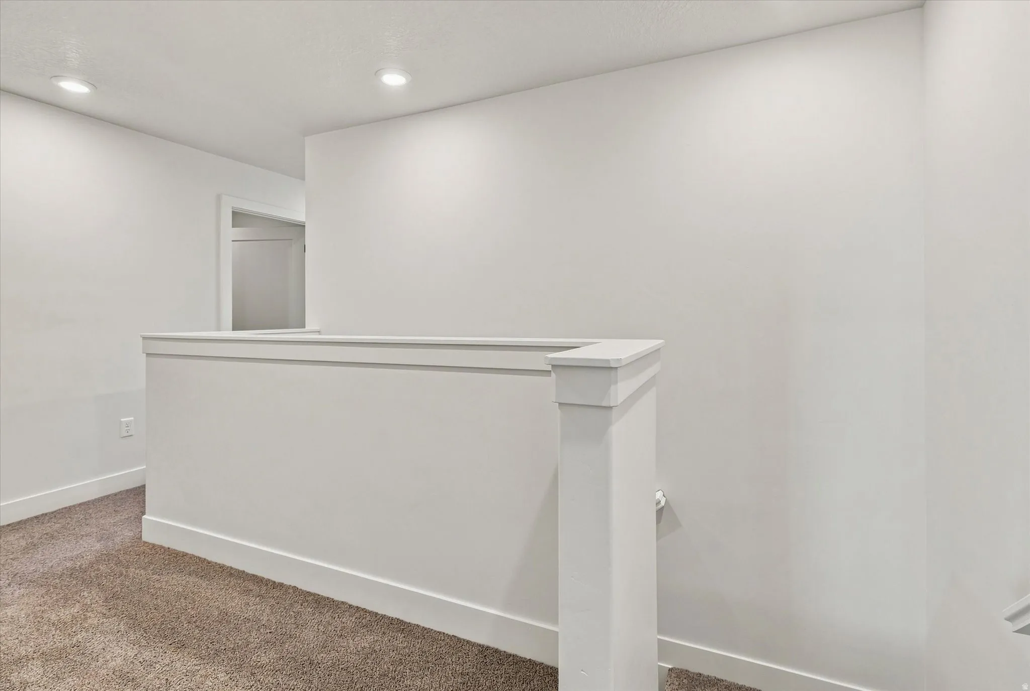 Recessed ceiling lighting, white painted walls, white trim, and carpeted flooring