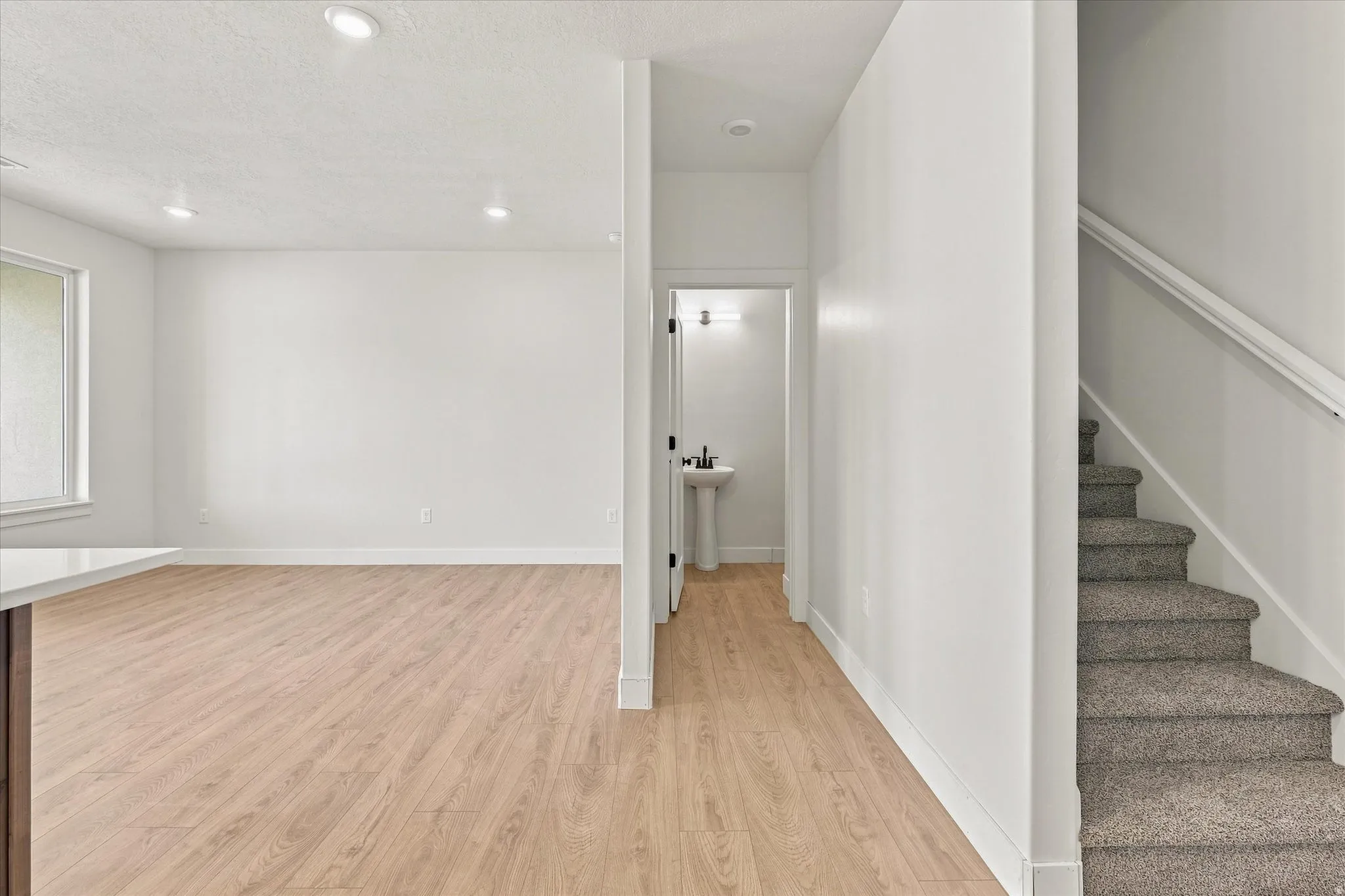 Expansive room with wood-finish flooring, recessed lighting, and a wide window