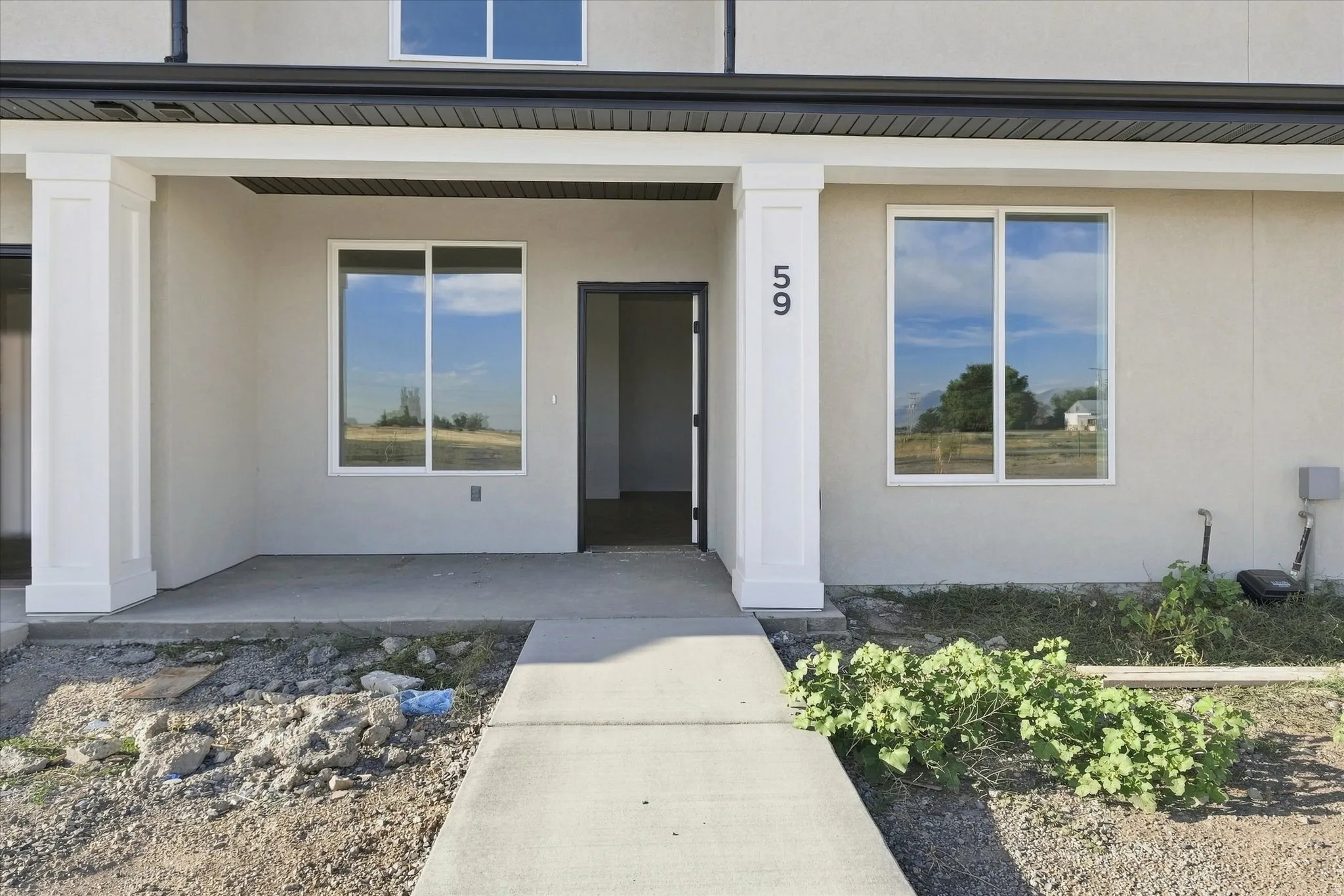 Covered entry with square columns, smooth stucco exterior, and black trim