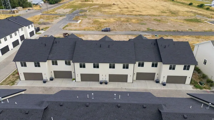 Townhome residences featuring light-toned siding, dark roofing, and attached garage doors