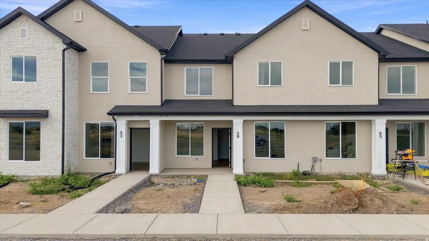 Modern townhome exterior featuring light-colored stucco and brick accents