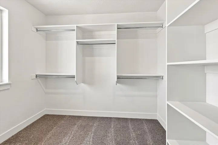 Built-in white shelving system with hanging rods, integrated shelving units, and plush carpeting