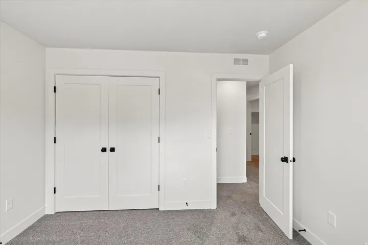 Light-colored carpet, white walls, white trim, and white doors with matte black hardware