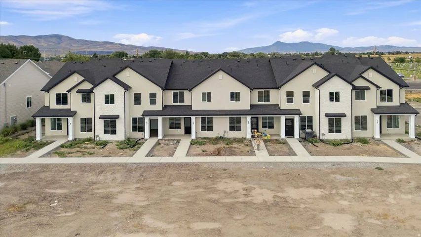 Modern townhome exteriors featuring light-colored siding, dark shingle roofing, and covered entryways