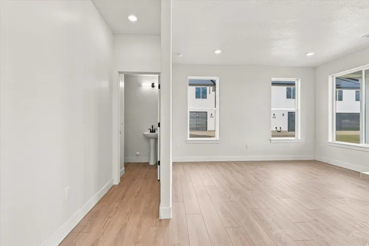 Recessed lighting, wood-finish flooring, multiple windows, and a pedestal sink with a matte black faucet