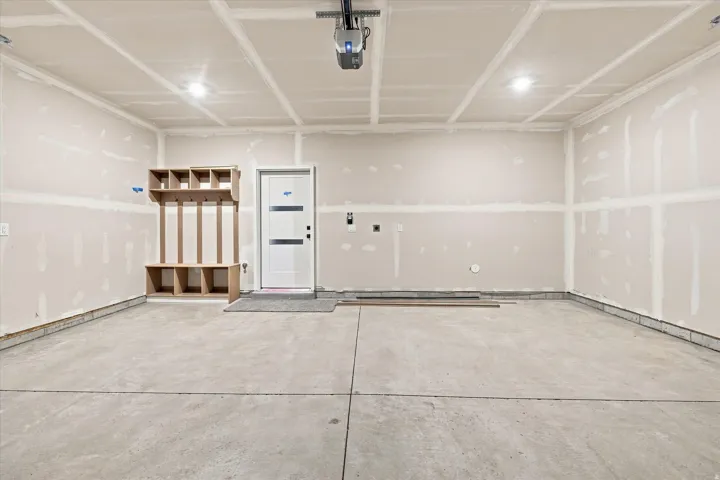 Spacious garage with exposed drywall, concrete flooring, and built-in storage shelving