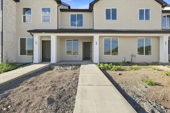 Stucco exterior, covered entryways, multiple large windows, and concrete walkways