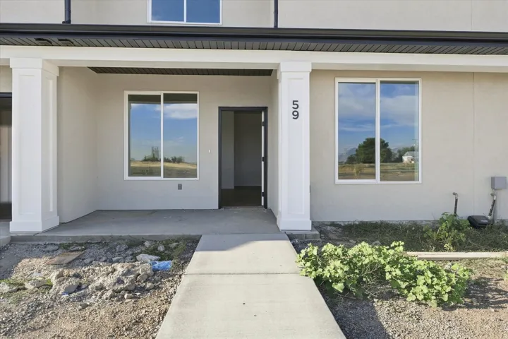 Covered entry with square columns, smooth stucco exterior, and black trim