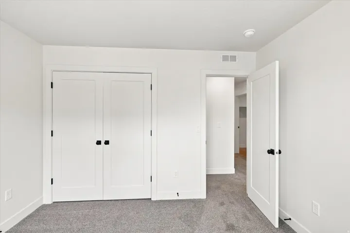 Plush carpeting, white walls, white trim, white paneled doors with matte black hardware