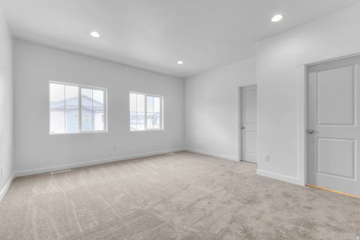 Recessed ceiling lighting, light-toned carpeting, white interior doors with satin nickel hardware, and multiple windows