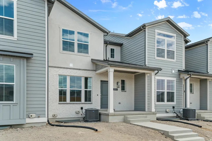 Multi-level exterior featuring light gray siding, white painted brick, and a covered entry