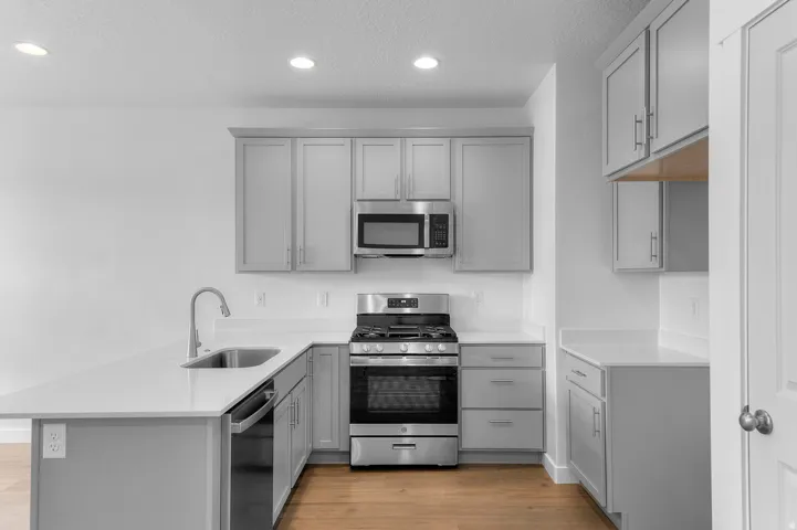 Kitchen featuring light grey cabinetry, stainless steel appliances, white countertops, recessed lighting, and wood-finish flooring