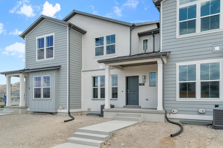 Modern townhome exterior featuring light gray siding and white brick accents