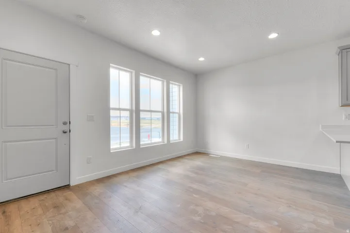 Spacious room featuring wood-finish flooring, white walls, and recessed lighting