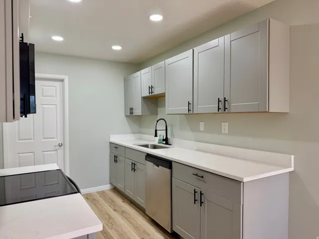 Kitchen featuring gray shaker-style cabinetry, stainless steel dishwasher, white countertops, wood-finish flooring, and recessed lighting