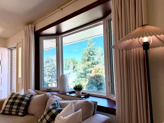 Bay window with a wood-finish sill, flanked by full-length drapery