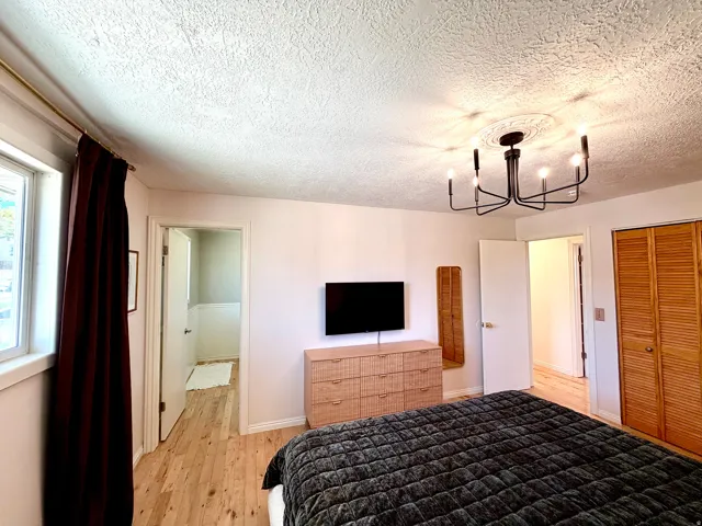 Wood-finish flooring, white walls, and a contemporary chandelier with a decorative ceiling medallion