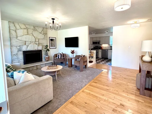 Stone-clad fireplace with mantel, recessed firebox, wood-finish flooring, and recessed lighting