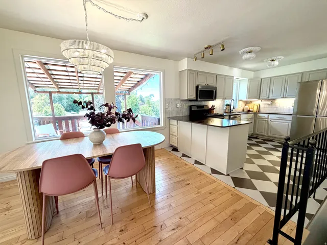 Expansive windows, wood-finish flooring, kitchen island with dark countertop, checkered tile flooring, and a decorative chandelier