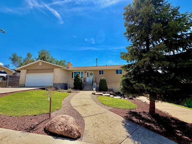 Front exterior featuring a stamped concrete walkway, integrated garage, mature landscaping, brick accents, and a prominent entry