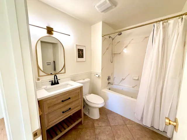 Wood-finish vanity with drawer storage, white countertop, and black-finish faucet
