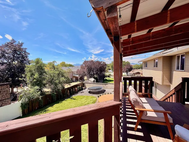 Exterior deck with wood-finish railing, wood-finish beams, string lighting, and direct access to a grassy yard
