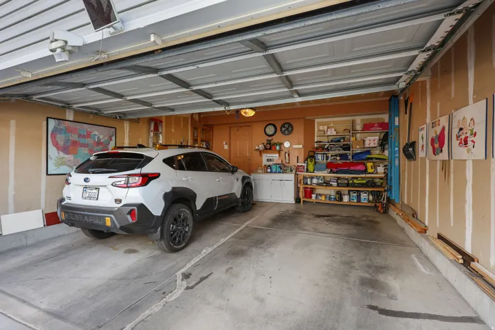 Attached garage featuring a concrete floor, exposed wall studs, and overhead lighting