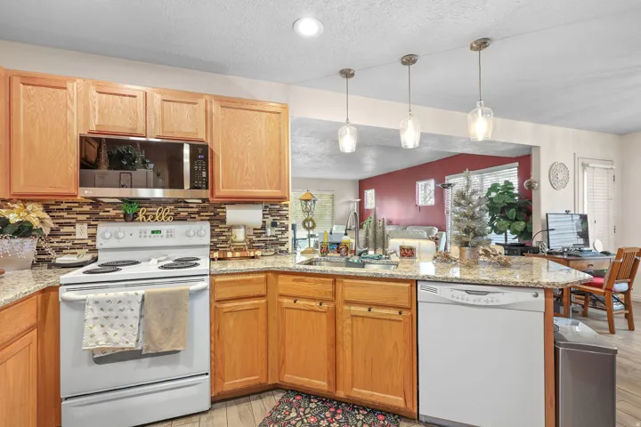 Kitchen featuring wood-finish cabinetry, granite-style countertops, mosaic tile backsplash, and an integrated over-the-range microwave