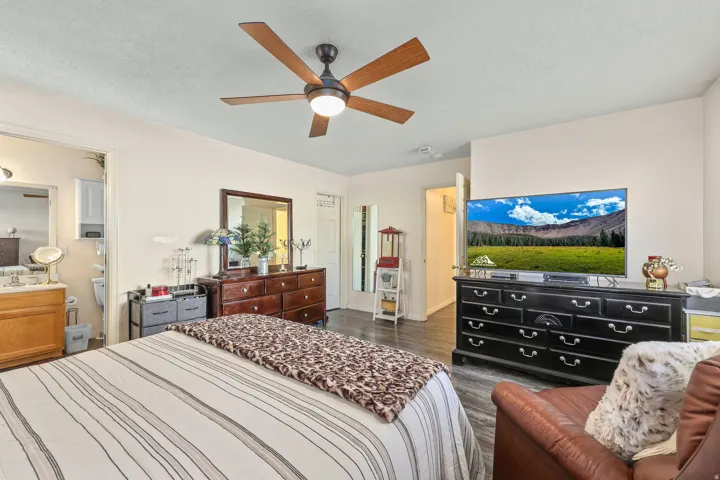 Wood-finish flooring throughout the room with a ceiling fan overhead