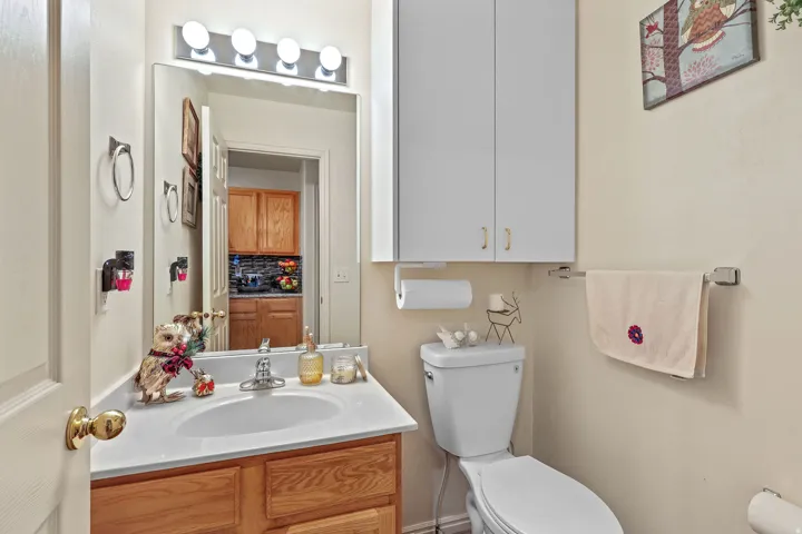 Vanity with wood-finish cabinetry, white countertop, and integrated sink