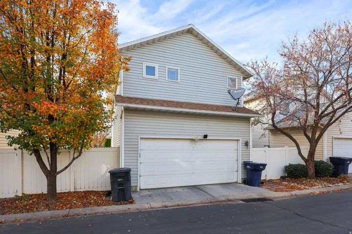 Two-story residence featuring light-colored siding, a two-car garage, and multiple upper-level windows