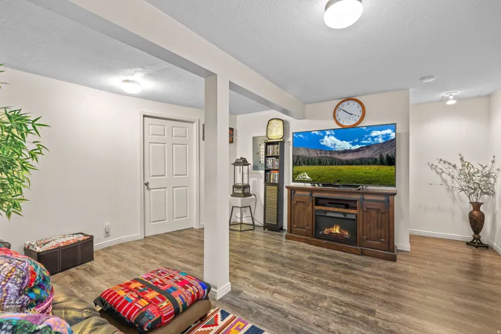 Spacious room featuring wood-finish flooring, white paneled door, and recessed lighting