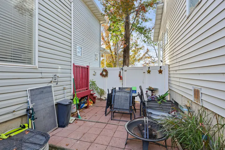 Paved patio area, white privacy fencing, red-painted wood deck, and vinyl siding exterior