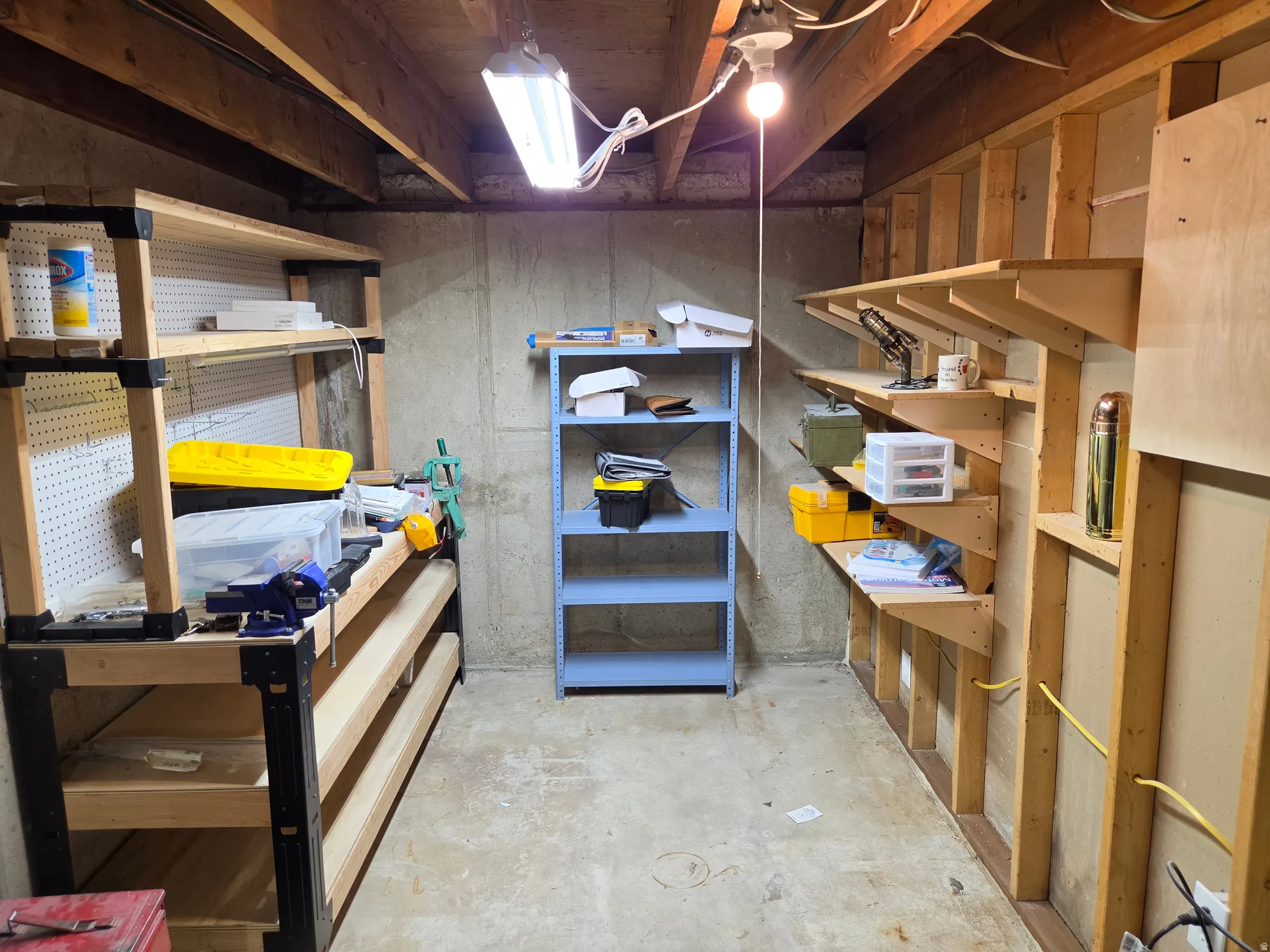 Unfinished basement space with exposed concrete foundation, visible wood ceiling joists, and concrete flooring