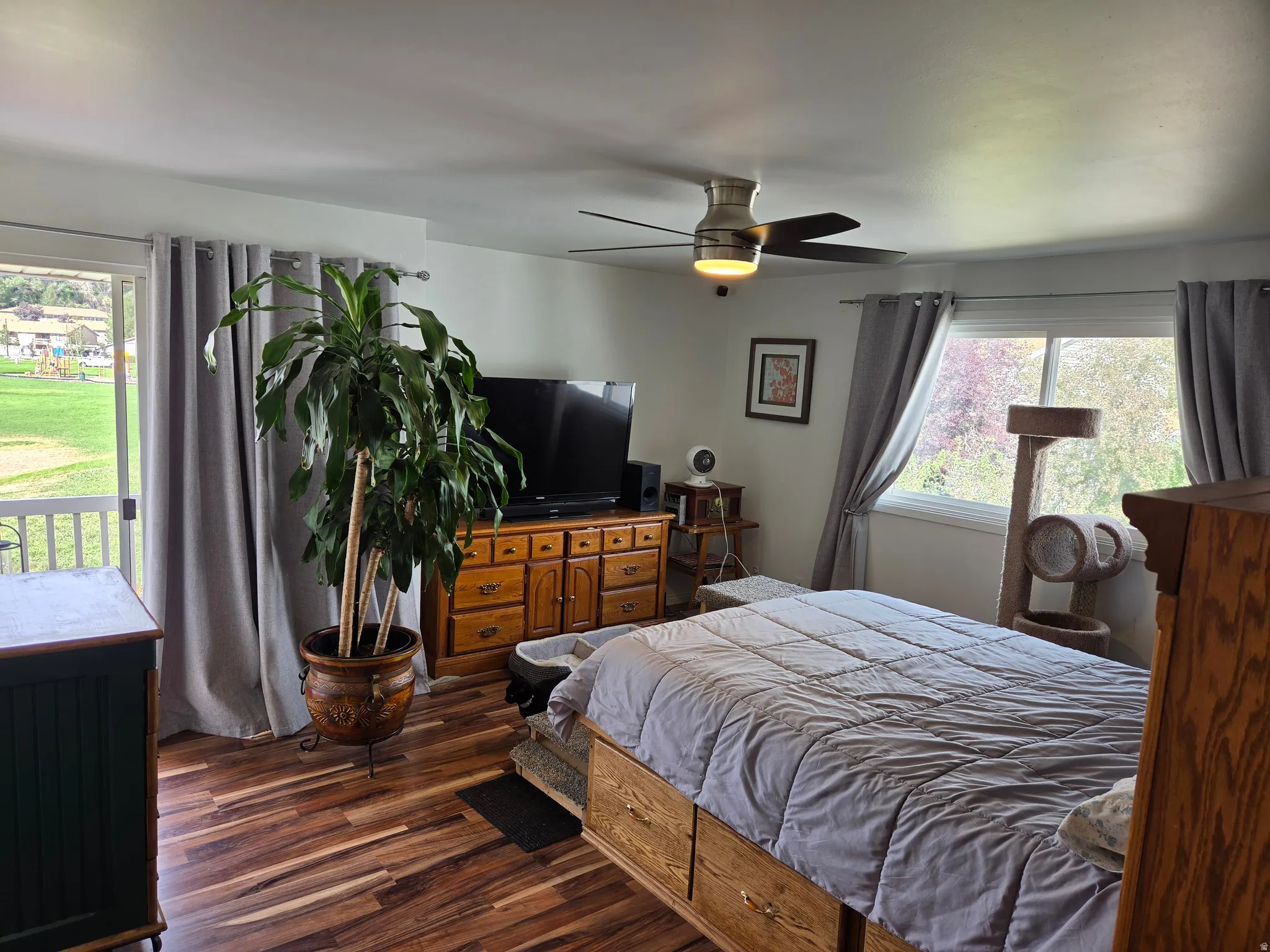 Wood-finish flooring, ceiling fan with integrated lighting, expansive window, and a sliding glass door