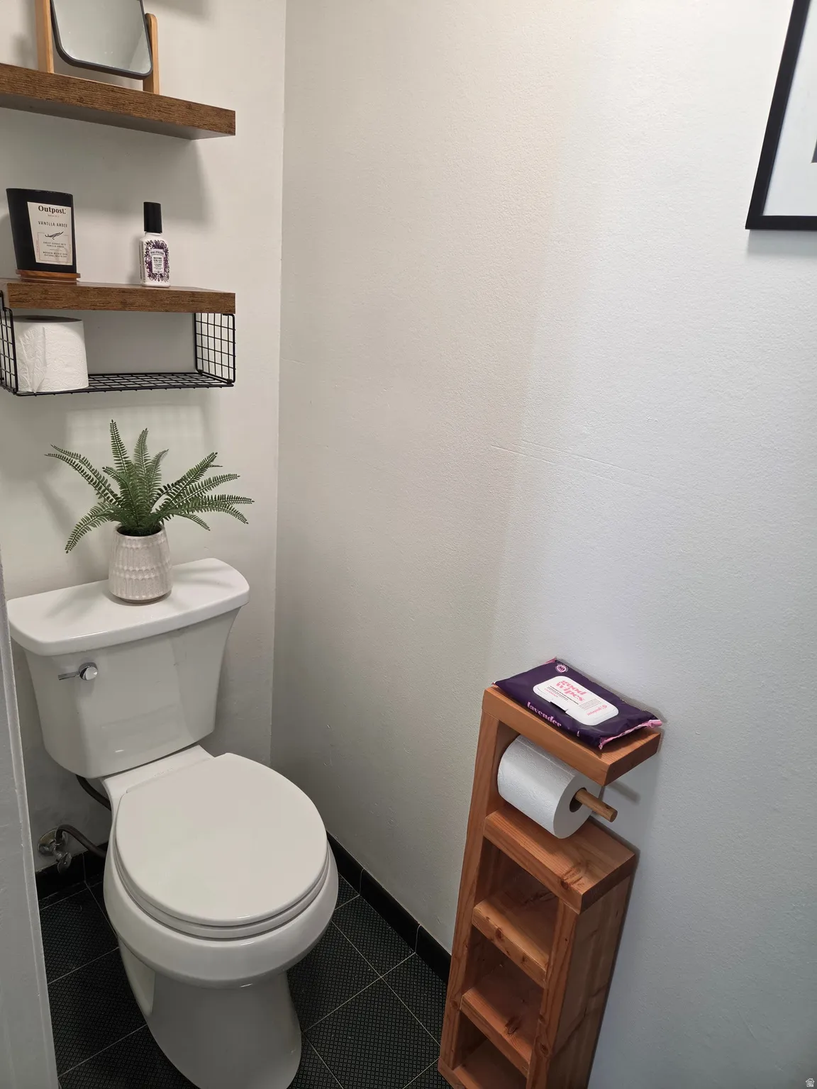 White toilet with dark tile flooring